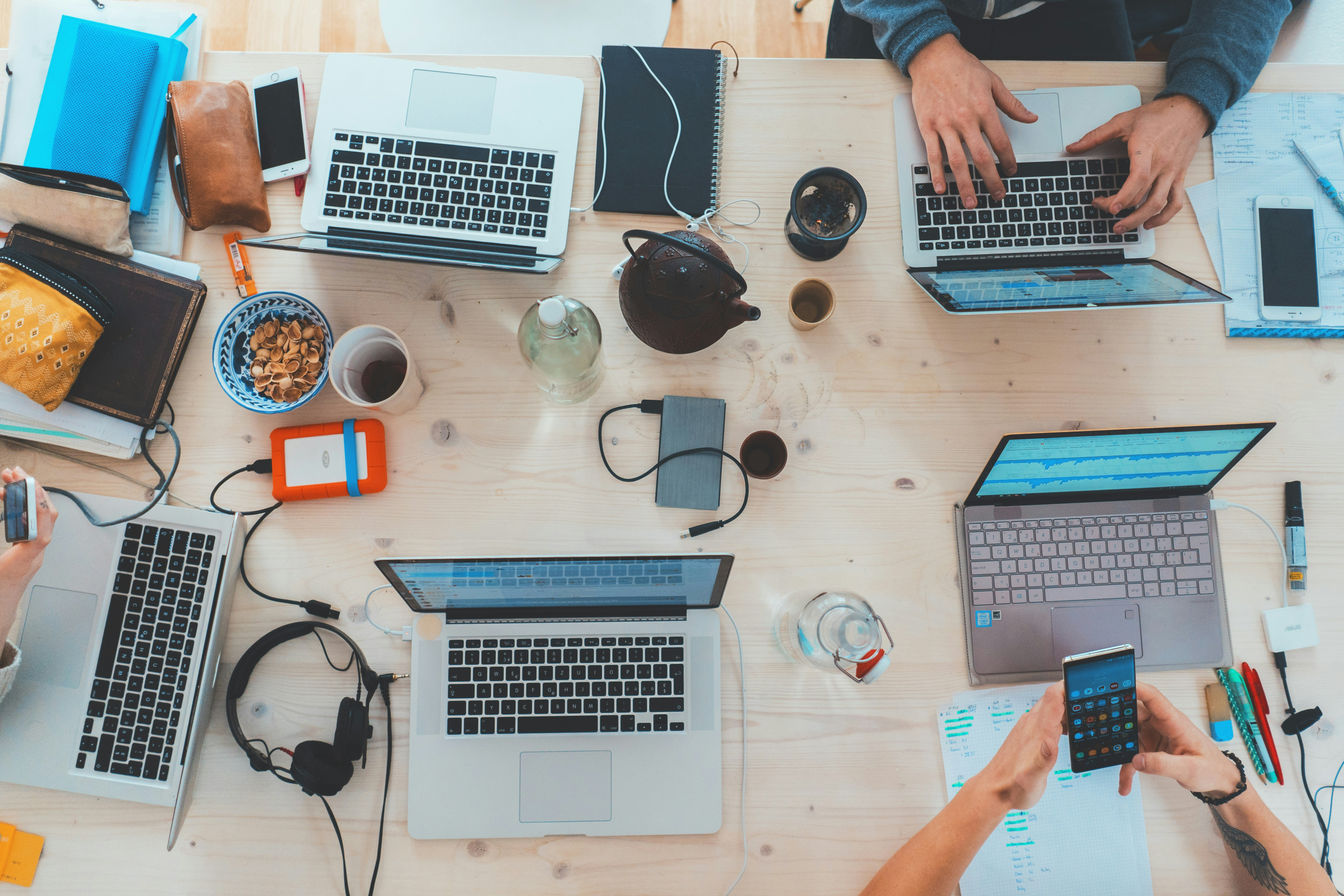 A group of people sitting together at a table. They are working on their laptops.